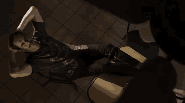 a man in a blue shirt is laying on the floor with his hands behind his head