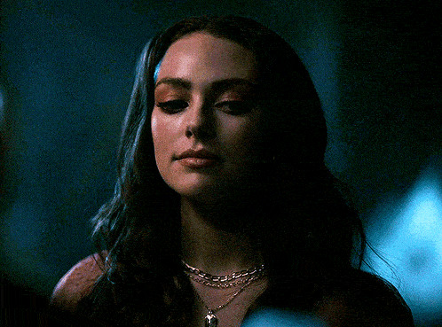 a close up of a woman wearing a necklace and earrings in a dark room .
