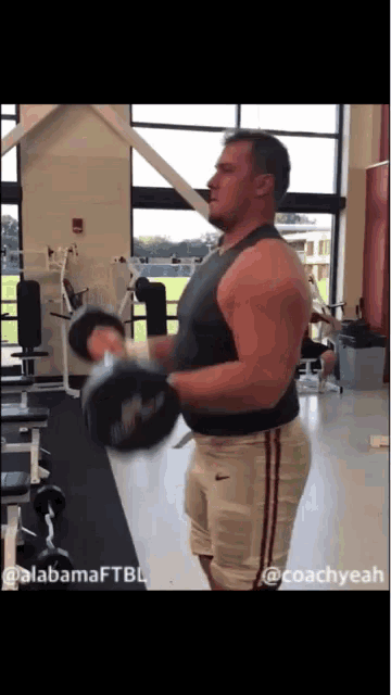 a man is lifting a dumbbell in a gym with alabamaftbl written on the bottom