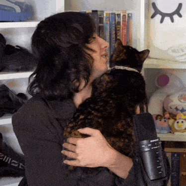 a person holding a cat in front of a microphone that says ' microphone ' on the front
