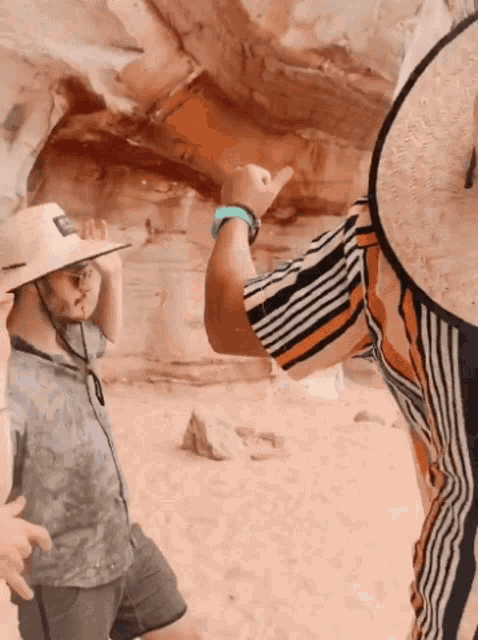 a man wearing a straw hat and a striped shirt is giving a thumbs up
