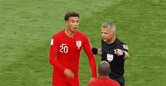 two soccer players are talking to each other on the field .