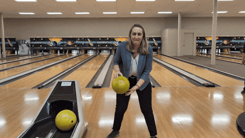 a woman in a bowling alley with a yellow ball