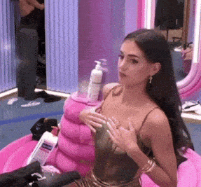 a woman is sitting in a pink chair with a bottle of dove lotion on it
