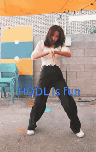 a woman is dancing in front of a wall with the words hodl is fun below her