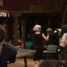 a group of people are playing ping pong in front of a speed 1 sign