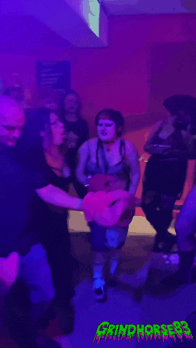 a group of people are dancing in a room with purple lights and a sign that says grinchfest