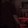 a man in a red shirt is standing in front of a shelf with red lights on it