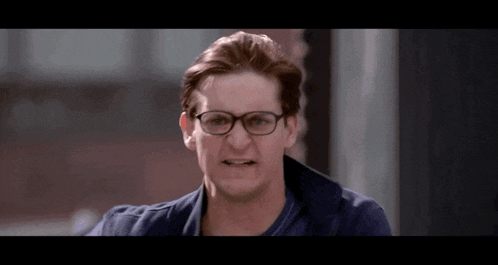 a man wearing glasses and a blue shirt is making a face