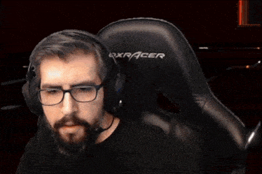 a man with glasses and a beard is holding a gun and smiling