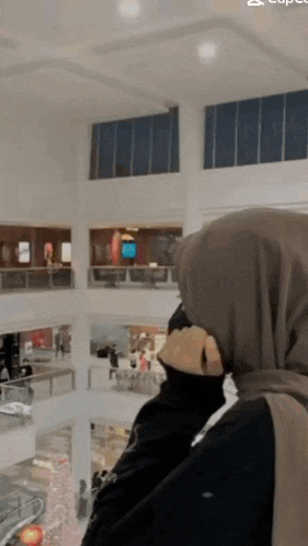 a woman in a hijab is taking a picture of a shopping mall .