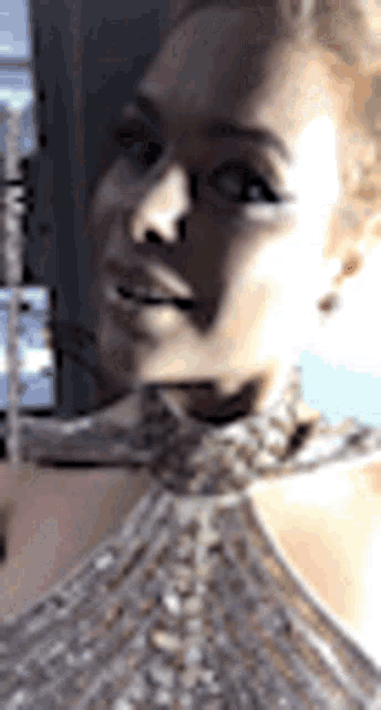 a close up of a woman 's face wearing a choker necklace and earrings .