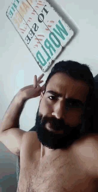 a shirtless man with a beard is taking a selfie in front of a sign that says world