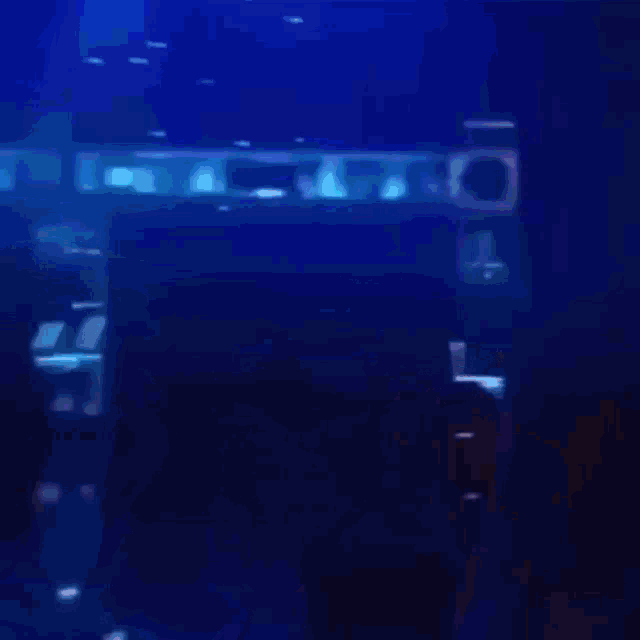 a blurry picture of a woman in a dark room with a blue background