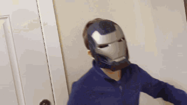 a man wearing a iron man helmet is standing in a room .