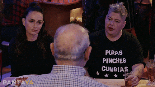 a woman wearing a puras pinches cumbias shirt sits at a table