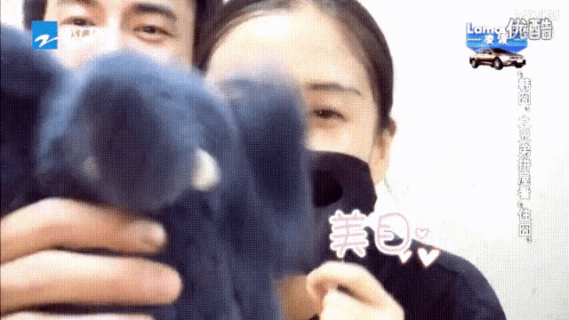 a man and a woman are holding a stuffed animal with chinese writing on the bottom right
