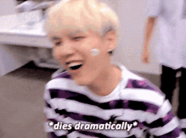a young man in a purple and white striped shirt is laughing and says " dies dramatically "