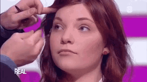 a woman is getting her hair done by a man on a tv show .