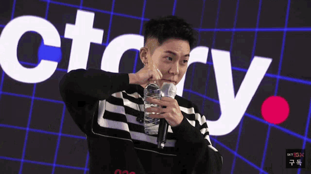 a man holds a bottle of water in front of a sign that says victory