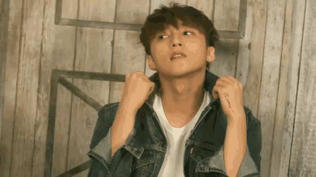 a young man in a denim jacket has a tattoo on his arm that says " i love you "