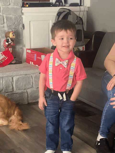 a little boy wearing a bow tie and suspenders stands in front of a box that says ' disney ' on it