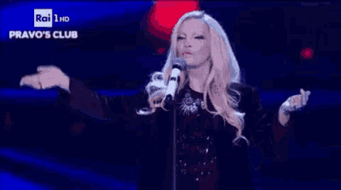 a woman singing into a microphone with the words pravo 's club on the screen behind her