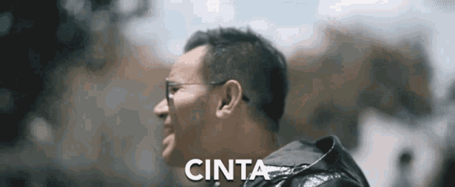 a man wearing glasses and a black jacket with the word cinta written below him