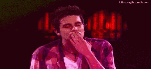 a man in a plaid shirt is covering his mouth with his hand while yawning .