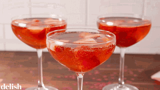 three wine glasses filled with red liquid with the word delish on the bottom right