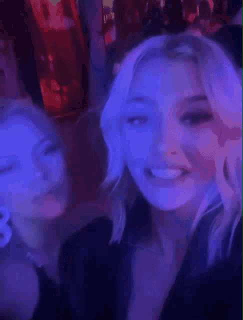 two women are standing next to each other in a dark room with blue lights .
