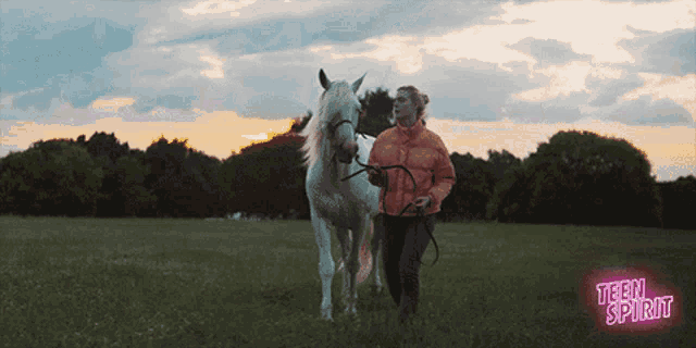 a girl walking a white horse in a field with teen spirit written in pink
