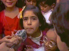 a little girl is being interviewed by a man in front of a microphone with the letter o on it .