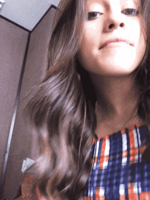 a close up of a woman 's face with a plaid shirt