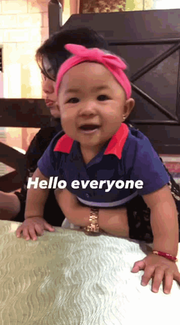 a baby with a pink headband is being held by a woman with the words hello everyone written on the bottom
