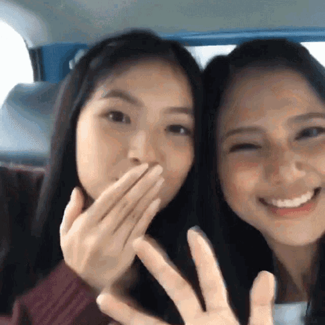 a woman covering her mouth with her hand while another woman looks on