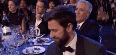 a man in a tuxedo and bow tie is sitting at a table with plates of food .