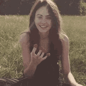 a woman is sitting in the grass holding strawberries in her hands .