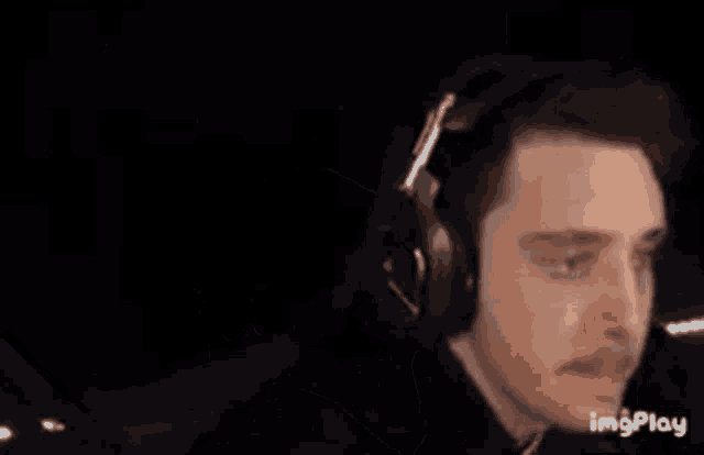 a man wearing headphones and a mustache is looking at something in the dark .