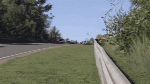 a car is going down a grassy hill with a fence in the foreground