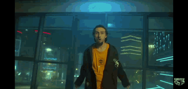 a man wearing a timberland t-shirt stands in front of a window