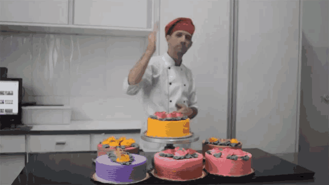 a man in a chef 's hat is standing in front of a table with cakes on it
