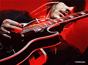 a man is playing a guitar with a red background and the words airbaggifs on the bottom