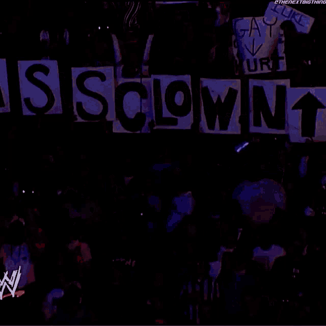 a crowd holds up signs that say assclown