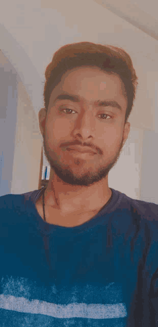a man with a beard wearing a blue shirt takes a selfie