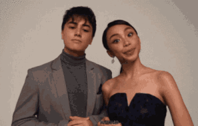a man in a suit and a woman in a dress pose for a photo