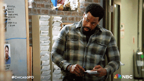 a man in a plaid shirt is writing on a piece of paper in front of a whiteboard with chicagopd written on it
