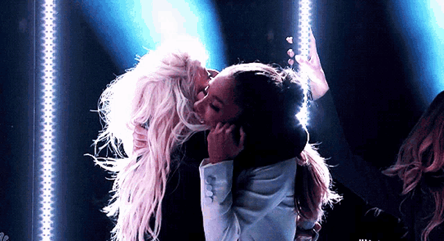 two women are hugging each other in front of a blue background