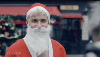 a man in a santa suit is standing in front of a christmas tree