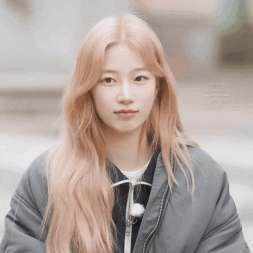 a woman with blonde hair is wearing a gray jacket